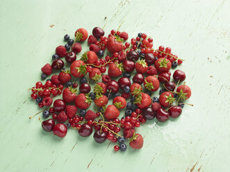 Overhead view of red summer fruits on green background - CUF19786