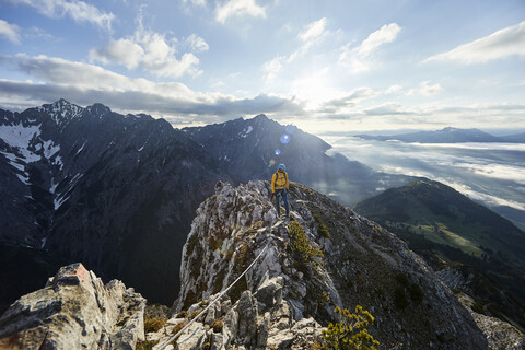 Österreich, Tirol, Gnadenwald, Hundskopf, männlicher Bergsteiger im Morgenlicht am Fels stehend, lizenzfreies Stockfoto