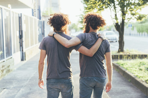 Rear view of identical male adult twins strolling on sidewalk - CUF19802