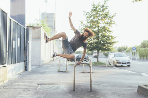 Junger männlicher Hipster, der auf dem Bürgersteig die Absätze hochkickt, lizenzfreies Stockfoto