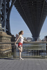 Junge Frau beim Sport im Freien, Stretching, unter der Williamsburg Bridge, New York City, USA - CUF19882