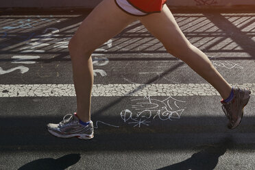 Young woman exercising outdoors, running, low section - CUF19887