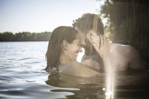 Couple face to face hugging, smiling in water, Berlin, Germany - CUF19937