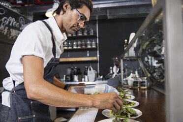 Restaurateur preparing salad behind service counter - CUF20024