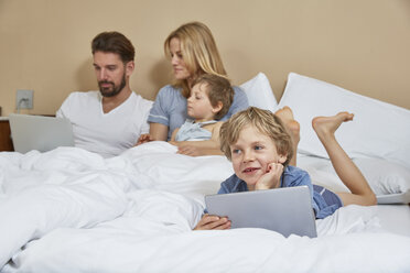 Mutter und Vater im Bett mit Söhnen, die Technik benutzen - CUF20028