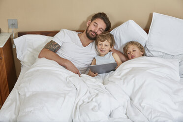 Father and sons in bed using digital tablet - CUF20030