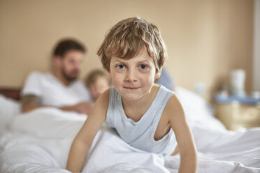 Junge auf dem Bett der Eltern schaut lächelnd in die Kamera - CUF20032