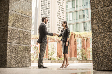 Businessman and woman shaking hands outside office, Dubai, United Arab Emirates - CUF20055