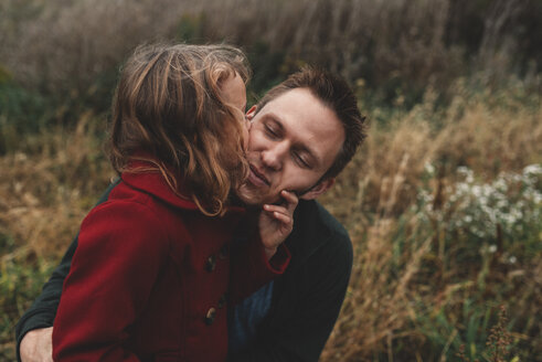 Mädchen küsst Vater auf die Wange im Feld - ISF07431