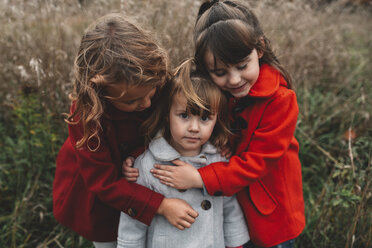 Portrait of two girls hugging toddler sister in field - ISF07434