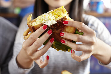 Young woman eating fast food, mid section, close-up - ISF07437