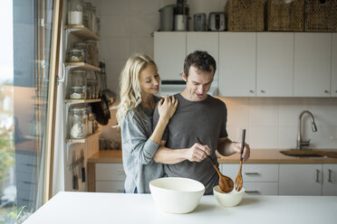 Mittleres erwachsenes Paar mischt Salatschüssel in Küche - ISF07443
