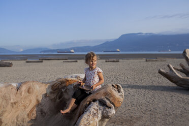 Kleines Mädchen spielt auf einer Holzskulptur am Strand, Vancouver, British Columbia, Kanada - ISF07448