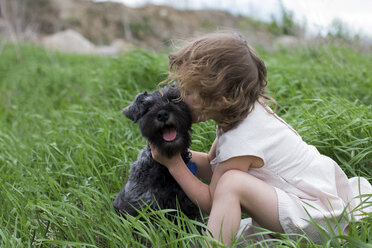 Kleines Mädchen küsst Haustier Hund auf Gras Feld - ISF07450