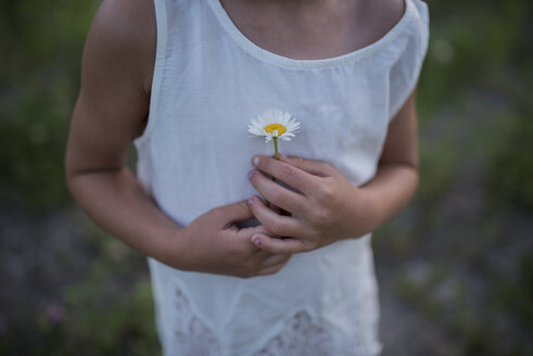 Kleines Mädchen hält Blume gegen Brust - ISF07451