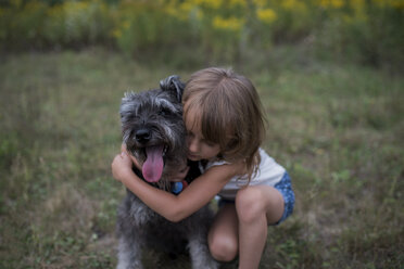 Kleines Mädchen umarmt Haustier Hund auf Gras Feld - ISF07452