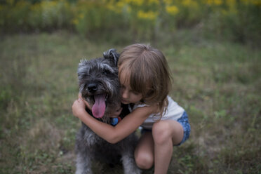 Little girl hugging pet dog on grass field - ISF07452