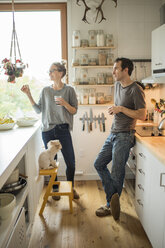 Mid adult couple with red wine chatting in kitchen - ISF07461