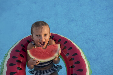 Young girl in swimming pool, relaxing on inflatable ring, eating watermelon - ISF07468