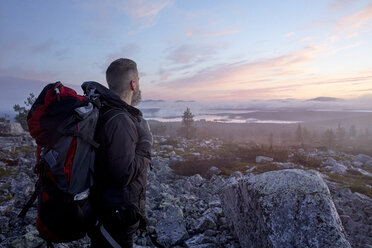 Wanderer genießt den Sonnenuntergang auf einer Klippe, Sarkitunturi, Lappland, Finnland - CUF20094