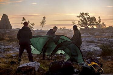 Hikers setting up tent at sunset, Sarkitunturi, Lapland, Finland - CUF20096