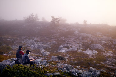 Wanderer entspannen sich mit Kaffee auf einem felsigen Feld, Sarkitunturi, Lappland, Finnland - CUF20103