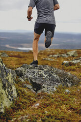 Mann beim Trailrunning auf einer felsigen Klippe, Keimiotunturi, Lappland, Finnland - CUF20110