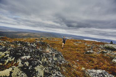 Mann beim Trailrunning auf einer felsigen Klippe, Keimiotunturi, Lappland, Finnland - CUF20111
