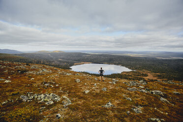 Trailrunner mit Blick auf eine felsige Klippe, Keimiotunturi, Lappland, Finnland - CUF20112