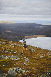 Mann beim Trailrunning auf einer felsigen Klippe, Keimiotunturi, Lappland, Finnland - CUF20114