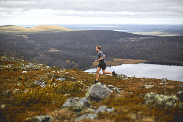 Mann beim Trailrunning auf einer felsigen Klippe, Keimiotunturi, Lappland, Finnland - CUF20115