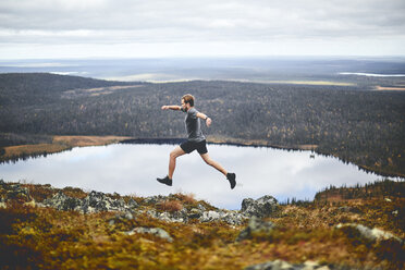 Mann sprintet auf felsiger Klippe, Keimiotunturi, Lappland, Finnland - CUF20116