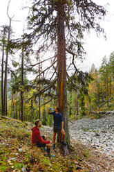 Trailrunner ruhen sich an einem Baum im Wald aus, Kesankitunturi, Lappland, Finnland - CUF20127