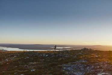 Mann beim Trailrunning auf einer Klippe bei Sonnenuntergang, Keimiotunturi, Lappland, Finnland - CUF20133