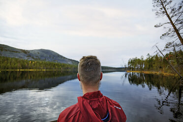 Man looking at lake view, Kesankijarvi, Lapland, Finland - CUF20135