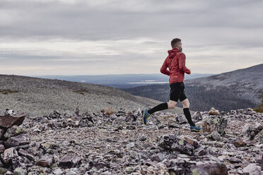 Mann beim Trailrunning auf einer felsigen Klippe, Kesankitunturi, Lappland, Finnland - CUF20136