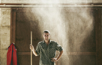 Portrait of young male farmworker in dusty farm barn - CUF20156