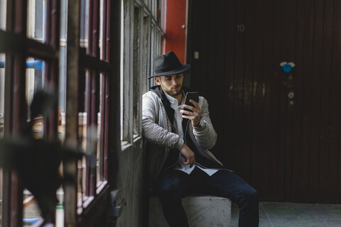 Bärtiger Mann mit schwarzem Hut, der ein Smartphone benutzt, lizenzfreies Stockfoto