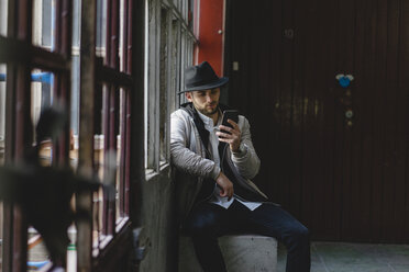 Bearded man wearing black hat, using smartphone - AFVF00597