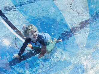 Porträt eines kleinen Jungen, der sich mit einem Bechball und einem Schwimmbad vergnügt - MUF01535