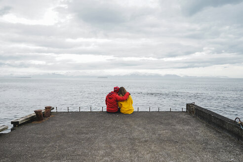 Island, Nordisland, Rückenansicht eines Paares, das auf einem Steg sitzt und die Aussicht genießt - AFVF00600