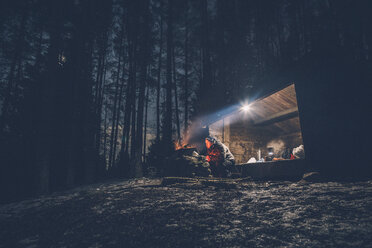 Sweden, Sodermanland, man at shelter with campfire at night - GUSF00911