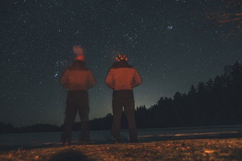 Schweden, Sodermanland, zwei Männer stehen am Seeufer unter nächtlichem Sternenhimmel - GUSF00915