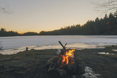 Schweden, Sodermanland, Lagerfeuer am Seeufer im Winter - GUSF00924