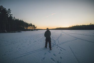 Sweden, Sodermanland, man walking on frozen lake Navsjon in winter - GUSF00930