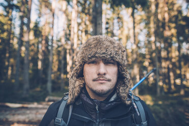 Schweden, Sodermanland, Porträt eines jungen Mannes mit Pelzmütze in abgelegener Landschaft - GUSF00934