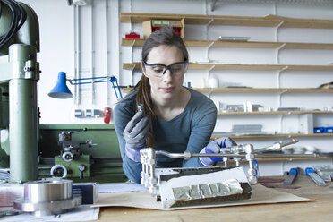 Frau mit Latexhandschuhen und Schutzbrille beim Bau eines Modells - CUF20345