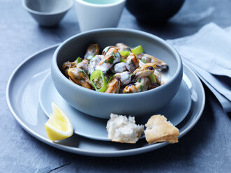 Mussels, leeks, sauce and herbs in bowl with lemon slice - CUF20354