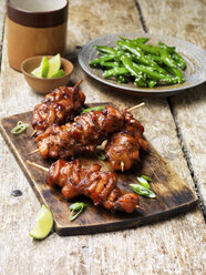 Barbecued teriyaki chicken kebabs on chopping board - CUF20357