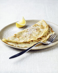 Pfannkuchen mit Zitronenspalte und Zucker auf dem Teller - CUF20365